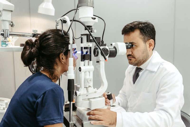 Male eye doctor examining the eyes of a female patient.
